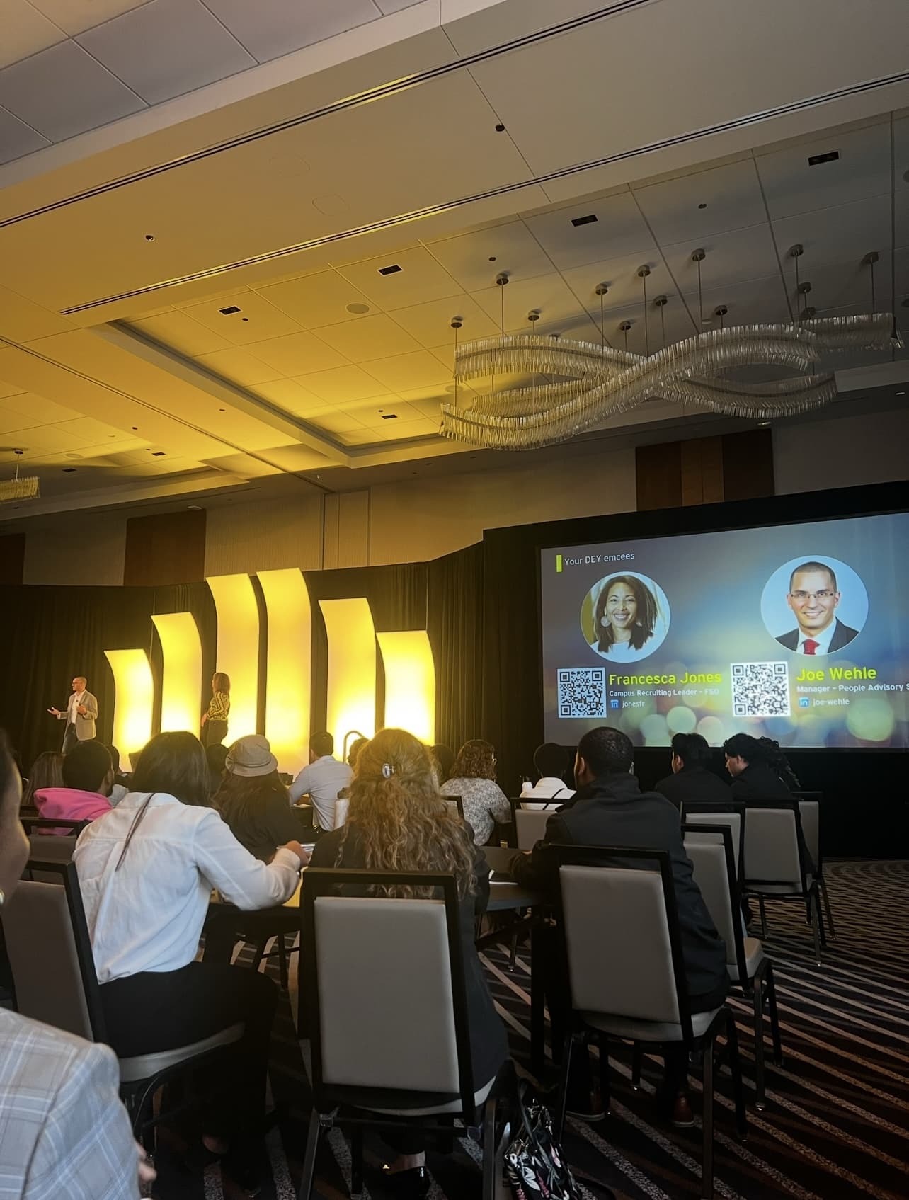Audience seated in a conference room watching an EY presentation on stage.