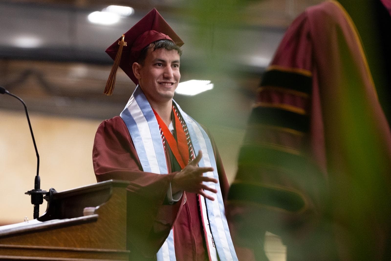 Lucas Cherniak smiling in a cap and gown at his Kutztown University graduation.